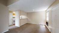 Located on Meadowwood Place in Colorado Springs, Colorado, this single-floor residence offers a functional and comfortable layout. The living area is spacious and open, featuring warm beige carpet, a textured ceiling, and a vaulted roofline that adds architectural interest. Baseboard heating runs along the perimeter walls, ensuring efficient climate control throughout. A pass-through counter connects the living area to the kitchen, maintaining an open and connected feel.

The galley-style kitchen is well-appointed with warm oak cabinetry, light countertops, a stainless steel sink, and white appliances including a range, refrigerator, dishwasher, and over-the-range microwave. The kitchen features durable hardwood-style flooring, providing a practical and clean surface.

The bedroom is generously sized and carpeted, with a large window that allows natural light to fill the room. Two closets offer ample storage, making the space highly functional. A baseboard heater is also present in this room.

The bathroom includes a full tub and shower combination, finished with classic white subway tile surround and chrome fixtures, providing a clean and timeless aesthetic.

The entry area features a paneled exterior door flanked by windows, opening into the main living space and completing this straightforward, well-designed single-floor home.
