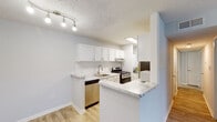 Located at 2323 Downing Ave in Savannah, Georgia, this single-floor residence offers a thoughtfully designed layout with updated finishes throughout. The kitchen is a standout feature, showcasing crisp white cabinetry with brushed nickel hardware, marble-look countertops, a stainless steel sink, and a full suite of stainless steel appliances including a gas range and dishwasher. A peninsula counter with a breakfast bar creates a seamless transition into the open living area. Track lighting illuminates the space, complementing the light-toned luxury vinyl plank flooring that extends through the main living areas. The spacious living room benefits from natural light and offers a clean, open canvas with neutral wall tones and a direct view into the kitchen. Bedroom spaces feature plush carpeting, textured ceilings, and windows dressed with horizontal blinds that provide both privacy and soft natural light. The bathroom is finished with white tile surrounding a full tub-shower combination, maintaining the home's clean, bright aesthetic. Throughout the residence, crisp white trim, neutral gray walls, and consistent finishes contribute to a cohesive and move-in-ready atmosphere well-suited to comfortable everyday living in Savannah.
