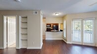 This 500 square foot one-bedroom apartment at Wellington Place in Olde Town offers a thoughtfully designed living space. The open-concept layout maximizes efficiency, seamlessly blending the kitchen and living areas. The kitchen features modern appliances, including a full-sized refrigerator, stove, and built-in microwave. Ample cabinetry in light wood tones provides generous storage, complemented by dark countertops for a sleek contrast.

The living room boasts rich wood-look flooring and is illuminated by large windows, flooding the space with natural light. A ceiling fan adds both style and functionality. French doors lead to a private balcony, extending the living space outdoors.

The bathroom is well-appointed with a single vanity, large mirror, and a combination tub/shower. Neutral tones throughout create a calming atmosphere. The bedroom, while not pictured, likely continues the apartment's modern aesthetic.

Overall, this apartment combines contemporary design with practical living, ideal for those seeking a compact yet comfortable urban dwelling.