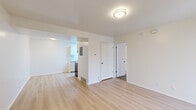 This well-maintained single-floor unit offers a thoughtfully laid-out interior finished with light hardwood flooring throughout the main living areas. The open living room is bright and airy, illuminated by a flush-mount ceiling light, and connects seamlessly to a separate room via a wide arched opening. A sliding glass door leads to a private balcony, bringing in natural light and providing outdoor access. The galley-style kitchen is efficiently designed with white cabinetry, light countertops, a stainless steel sink, and stainless steel appliances including a refrigerator and an electric range with overhead ventilation. A skylight enhances the kitchen's brightness. The bedrooms offer a comfortable retreat, with some rooms featuring soft carpeting and a window for natural light, while others continue the hardwood flooring. Closet access is conveniently located within the bedroom areas. The full bathroom is clean and functional, featuring a single vanity with under-cabinet storage, a wall mirror, and a shower-tub combination. Throughout the unit, white walls and neutral tones create a cohesive, move-in-ready atmosphere that is both practical and inviting.