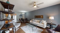 Located at 109 Orchard Hills Dr in Jeffersonville, Indiana, this single-floor residence offers a cohesive, thoughtfully designed layout with a neutral color palette anchored by cool gray accent walls and rich hardwood-style flooring throughout the main living areas.

The living room serves as the central gathering space, featuring a ceiling fan with a brass-toned fixture, a large sliding window that draws in natural light, and ample room for comfortable seating arrangements. The space flows seamlessly into the dining area, which is highlighted by a chandelier overhead and room for a full dining set. Adjacent to the dining area, the kitchen is equipped with warm oak cabinetry, stainless steel appliances including a gas range and microwave, a full-size refrigerator, and a peninsula with granite-style countertops that adds prep and serving space.

The bedrooms offer a quieter retreat, each with carpeted flooring, ceiling fans, and windows that bring in natural light. The bathroom includes a full tub and shower combination with clean white surrounds. A dedicated laundry area houses a full-size washer and dryer alongside a water heater, adding everyday convenience to the unit's practical design.