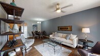 Located at 109 Orchard Hills Dr in Jeffersonville, Indiana, this single-floor residence offers a cohesive, thoughtfully designed layout with a neutral color palette anchored by cool gray accent walls and rich hardwood-style flooring throughout the main living areas.

The living room serves as the central gathering space, featuring a ceiling fan with a brass-toned fixture, a large sliding window that draws in natural light, and ample room for comfortable seating arrangements. The space flows seamlessly into the dining area, which is highlighted by a chandelier overhead and room for a full dining set. Adjacent to the dining area, the kitchen is equipped with warm oak cabinetry, stainless steel appliances including a gas range and microwave, a full-size refrigerator, and a peninsula with granite-style countertops that adds prep and serving space.

The bedrooms offer a quieter retreat, each with carpeted flooring, ceiling fans, and windows that bring in natural light. The bathroom includes a full tub and shower combination with clean white surrounds. A dedicated laundry area houses a full-size washer and dryer alongside a water heater, adding everyday convenience to the unit's practical design.