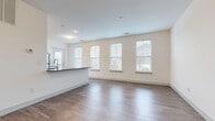 Located at 3511 Westbrook Blvd in East Islip, NY, this thoughtfully designed 2-bedroom, 2-bathroom residence offers a comfortable and modern living experience across a single floor. The open-concept layout seamlessly connects the living room and kitchen, with rich wood-look flooring and large windows that flood the space with natural light and provide pleasant neighborhood views. The kitchen is well-equipped with stainless steel appliances — including a gas range, over-the-range microwave, and refrigerator — complemented by white shaker-style cabinetry, gray countertops, and a breakfast bar. A private door in the kitchen leads to a balcony, adding outdoor access. The spacious primary bedroom features carpeted flooring, multiple windows, and a dedicated walk-in closet with built-in shelving. The second bedroom is equally bright, with soft carpet and generous natural light. Both bathrooms are finished with white vanities and marble-style tile flooring; the full bath includes a tiled tub-shower combination. Two hallways connect the space efficiently, and two closets provide ample storage. The clean, neutral color palette throughout creates a bright, move-in-ready atmosphere.