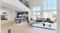 Located in the heart of Los Angeles, this contemporary two-story residence offers a thoughtfully designed layout across two floors. The expansive main level immediately impresses with soaring double-height ceilings in the living room, light wood flooring throughout, and crisp white walls that create a bright, airy atmosphere. A striking staircase leads to an open upper-level loft area, framed by sleek metal railings, which serves as a versatile lounge or study space. Both bedrooms are generously sized, bathed in natural light through large windows that frame panoramic views of the Los Angeles skyline and surrounding mountains. The primary bedroom features a dedicated sitting area with floor-to-ceiling corner windows, flooding the room with sunlight and city views. The second bedroom also benefits from direct outdoor access and ample natural light. The two bathrooms are finished with neutral-toned tile work; one includes a full soaking tub alongside a glass-enclosed walk-in shower. A dedicated laundry room with a stacked washer and dryer adds everyday convenience. Additional highlights include a hallway closet and two hallways connecting the living spaces. The overall aesthetic is clean, modern, and inviting — a refined urban retreat in a prime Los Angeles location.