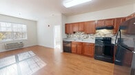 Located at 255 East Grand Avenue in Rahway, NJ, this 2-bedroom, 2-bathroom residence offers a well-organized single-floor layout designed for comfortable everyday living. The entrance opens into a bright living area with warm hardwood-style flooring that extends throughout the main spaces, allowing natural light to flow freely across the open floor plan.

The combined kitchen and dining area serves as the heart of the home, featuring rich cherry-toned cabinetry, a mosaic tile backsplash, light countertops, and a full suite of black appliances including a refrigerator, range, dishwasher, and microwave. Ample upper and lower cabinet storage makes the kitchen both functional and visually appealing.

Both bedrooms are carpeted and bathed in natural light from large windows with blinds. The primary bedroom is a comfortable size and includes access to a walk-in closet outfitted with wire shelving and storage racks. The second bedroom also offers generous proportions and easy access to the main living area.

The two bathrooms are finished with tile flooring and warm wood vanities. One features a glass-enclosed walk-in shower with tiled surround, while the other includes a shower-tub combination and a well-lit vanity mirror. Together, the bathrooms provide practical, clean finishes suited for daily use.