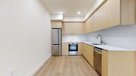 Located at 7050 Hawthorn Ave, Unit PH711 in Los Angeles, CA, this one-bedroom, one-bathroom penthouse unit offers a thoughtfully designed layout with a clean, modern aesthetic throughout. Light oak-toned hardwood flooring and crisp white walls create a bright, cohesive atmosphere across the entire space.

The open-concept main area seamlessly combines the living room, dining room, and kitchen into one functional zone. The kitchen is well-appointed with flat-front light wood cabinetry, white quartz countertops, stainless steel appliances including a refrigerator, range with oven, and dishwasher, and a undermount sink — all finished with a sleek tile backsplash. Recessed lighting throughout enhances the clean lines of the design.

The bedroom is a calm, well-proportioned retreat featuring a window for natural light, a sliding-door closet, and direct access to the laundry area. The bathroom offers a full soaking tub and shower combination with large-format light gray tile surround, a wood-accented vanity, and neutral tile flooring, maintaining the modern minimalist tone of the unit.

A bold dark-finished entry door anchors the living area and adds a contemporary contrast to the otherwise light and airy interior. The unit also benefits from a dedicated closet and in-unit laundry, providing practical convenience in a compact, efficient footprint.