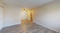 Located at 2001 Rockcreek Dr in Bowling Green, Kentucky, this single-floor unit offers a practical and well-maintained layout designed for comfortable everyday living. The living area greets you with durable wood-style laminate flooring in a warm gray tone, neutral beige walls, and a front entry door framed by a window that brings in natural light. A ceiling fan provides comfort overhead, and the open sightline connects seamlessly to an adjacent dining or secondary living area.

The kitchen is efficiently arranged in an L-shaped configuration, featuring white cabinetry, light countertops, and black appliances including a gas range with overhead ventilation and a full-size refrigerator. The wood-style flooring continues here, tying the common areas together cohesively.

The bedroom offers a calm, restful environment with plush wall-to-wall carpeting, neutral painted walls, and a window fitted with horizontal blinds for privacy and light control.

The bathroom is clean and functional, showcasing tile flooring, a white vanity with an integrated sink, matte black fixtures, and a large mirror. Two paneled doors provide access to additional storage or closet space, adding to the unit's practicality. Throughout, the space maintains a consistent, understated aesthetic suited to a variety of lifestyles.