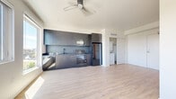 Located at 270 N Hancock St in Portland, Oregon, this modern one-bedroom, one-bathroom unit offers a thoughtfully designed open-concept layout across a single floor. Light wood-tone flooring flows continuously throughout the living areas, complementing the clean white walls and contemporary aesthetic.

The main living and kitchen area is anchored by a sleek, full-length kitchen featuring dark cabinetry, dark countertops, and a complete suite of stainless steel appliances including a refrigerator, electric range, microwave, and dishwasher. A ceiling fan overhead adds functionality to the space. Three large windows along the living area wall flood the interior with natural light and frame sweeping views of the Portland cityscape and surrounding tree canopy.

The bedroom is a bright, welcoming space with two generous windows that offer additional city views, allowing natural light to fill the room throughout the day. Light-toned flooring continues here, maintaining a cohesive design language.

The bathroom is clean and functional, finished with tile flooring in a warm wood-look tone, a soaking tub, toilet, and matte black hardware accents. The entry area provides access to a closet and in-unit washer/dryer connections, adding everyday convenience. Overall, the unit presents a crisp, modern living environment well-suited to urban Portland life.