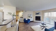 This single-floor residence offers a thoughtfully designed layout that balances comfort and functionality throughout. The open-concept living area is anchored by a classic white-mantled fireplace and flows seamlessly into the dining space, where wood-look flooring extends throughout and a ceiling fan overhead adds practical comfort. A large sliding glass door in the living room bathes the space in natural light and opens to a private outdoor patio, providing a welcoming indoor-outdoor connection.

The kitchen is efficiently designed with white cabinetry, dark granite-style countertops, and stainless steel appliances including a refrigerator, range, and over-the-range microwave. A dedicated pantry with built-in shelving offers generous storage. Adjacent to the kitchen, the dining area comfortably accommodates a full dining set and conveniently sits next to an in-unit laundry area.

The primary bedroom features plush carpeting, warm neutral tones, and ample space, complemented by an en-suite bathroom with white cabinetry, dark countertops, wood-look flooring, a walk-in closet, and a separate water closet. A second bedroom mirrors the same comfortable, carpeted ambiance with soft neutral walls. The textured ceilings are consistent throughout, contributing to the home's cohesive, residential character.