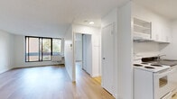 Located on Rue Prince Arthur Ouest in the heart of Montréal, this one-bedroom, one-bathroom unit offers a clean, modern aesthetic throughout. Light hardwood flooring runs continuously across the living spaces, creating a warm and cohesive feel from room to room.

The living room is the focal point of the unit, featuring a large black-framed window that invites an abundance of natural light and frames pleasant views of the surrounding greenery. The bright, white walls enhance the sense of openness, making the space feel airy and welcoming.

The kitchen is efficiently designed with ample white cabinetry extending to the ceiling for generous storage, dark countertops providing a striking contrast, and tile flooring. It includes a full-size refrigerator, stove, and sink, offering all essential amenities in a well-organized layout.

The bedroom is a comfortable, well-proportioned retreat with its own window providing natural light and outdoor views. A set of mirrored sliding closet doors adds both storage and the illusion of additional space.

The bathroom is finished in a neutral palette, featuring tile flooring, a bathtub, toilet, and a white vanity, maintaining the clean and functional character found throughout the unit. The overall ambiance is bright, minimal, and move-in ready.