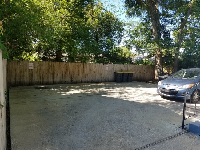 Concrete parking area behind the building that's well lighted. - 1564 W 14th St Apartments