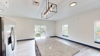 This thoughtfully designed two-story home offers three bedrooms and two bathrooms across two well-proportioned floors. A consistent design language ties the space together, featuring light wood-look flooring, crisp white walls, and striking navy blue trim, doors, and cabinetry throughout.

The kitchen is a standout feature, boasting navy shaker-style cabinetry, granite countertops with a large central island, white subway tile backsplash, and a full suite of stainless steel appliances. A geometric pendant light fixture adds a modern industrial touch, and sliding glass doors open to an outdoor balcony with green, open views.

Both bathrooms echo the kitchen's design palette, with granite-topped navy vanities, light wood-look flooring, and classic white subway tile surrounding the tub and shower areas.

The bedrooms are bright and airy, each filled with natural light from multiple windows overlooking the surrounding neighborhood. The primary bedroom enjoys direct balcony access through sliding glass doors and includes a ceiling fan. Additional bedrooms feature built-in closets with navy doors and ceiling fans. 

Throughout the home, the cohesive use of navy accents against neutral tones creates a clean, contemporary aesthetic, while generous window placement ensures each room feels open and connected to the outdoors.