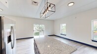 This thoughtfully designed two-story home offers three bedrooms and two bathrooms across two well-proportioned floors. A consistent design language ties the space together, featuring light wood-look flooring, crisp white walls, and striking navy blue trim, doors, and cabinetry throughout.

The kitchen is a standout feature, boasting navy shaker-style cabinetry, granite countertops with a large central island, white subway tile backsplash, and a full suite of stainless steel appliances. A geometric pendant light fixture adds a modern industrial touch, and sliding glass doors open to an outdoor balcony with green, open views.

Both bathrooms echo the kitchen's design palette, with granite-topped navy vanities, light wood-look flooring, and classic white subway tile surrounding the tub and shower areas.

The bedrooms are bright and airy, each filled with natural light from multiple windows overlooking the surrounding neighborhood. The primary bedroom enjoys direct balcony access through sliding glass doors and includes a ceiling fan. Additional bedrooms feature built-in closets with navy doors and ceiling fans. 

Throughout the home, the cohesive use of navy accents against neutral tones creates a clean, contemporary aesthetic, while generous window placement ensures each room feels open and connected to the outdoors.
