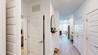 Located at 409 Pratt Ave NE in Huntsville, Alabama, this thoughtfully designed single-floor unit makes excellent use of its compact footprint. A welcoming entryway corridor with light wood-look flooring, crisp white walls, and a built-in wall shelf leads into the main living space. The open-concept kitchen is a standout feature, showcasing two-tone cabinetry with light upper panels and gray lower cabinets, white subway tile backsplash, light quartz countertops, and a full suite of stainless steel appliances including a refrigerator, range, microwave, and dishwasher. A small kitchen island provides additional prep space and casual seating. The combined living area is accented by a soothing blue accent wall, recessed lighting, a ceiling fan, and natural light from a window with white curtains — creating a warm, inviting atmosphere. The bathroom is cleanly appointed with gray cabinetry, a granite-topped vanity, a large framed mirror, modern vanity lighting, and wood-look tile flooring. Throughout the unit, consistent flooring and a neutral-yet-stylish color palette contribute to a cohesive and modern aesthetic well-suited for contemporary living.
