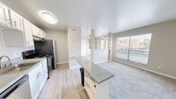 Located at 611 Lead Ave SW in Albuquerque, New Mexico, this efficiently designed single-floor unit offers a well-organized layout that maximizes every square foot. The open-concept kitchen and living area form the heart of the space, with light wood-look flooring in the kitchen transitioning seamlessly to plush carpet in the living area. The kitchen is equipped with stainless steel appliances, including a refrigerator and range, complemented by crisp white cabinetry and a peninsula counter with a stone-look surface that doubles as a breakfast bar. A built-in open shelving unit acts as a subtle divider between the kitchen and living area, adding both function and visual interest. The living area is bright and airy, benefiting from a large window with horizontal blinds that allows natural light to fill the room. The bedroom continues the carpeted flooring and features a ceiling fan with light fixture, a sliding-door closet for ample storage, and a built-in dresser unit beneath a large window overlooking the surrounding neighborhood. The bathroom offers a clean, classic aesthetic with full white square tile surrounding a soaking tub and shower combination, fitted with brushed nickel fixtures. Throughout, neutral wall tones and clean white trim create a cohesive, move-in-ready environment.