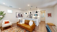 Located at 13939 FM-1560 in San Antonio, TX, this two-story home offers a thoughtfully designed layout spread across two well-proportioned floors. The main level features an open-concept living room and kitchen that flow seamlessly together. The living area is bright and inviting, with recessed lighting, light hardwood-style flooring, and multiple windows that allow generous natural light to fill the space. The kitchen is a standout, boasting crisp white shaker cabinets, a large waterfall-edge island with an undermount sink and bar seating, stainless steel appliances, a subway tile backsplash, and striking matte black pendant lights overhead — a clean, contemporary aesthetic throughout. The upper level hosts the primary bedroom, a generously sized and serene retreat featuring vaulted ceilings, plush carpet, a ceiling fan, and access to a spacious walk-in closet outfitted with extensive built-in shelving and hanging rods. Two full bathrooms serve the home, each finished with white cabinetry, matte black fixtures, and tiled surrounds. Hallways and staircases connect the floors efficiently. The overall ambiance is modern and cohesive, with a neutral palette, quality finishes, and a functional floor plan well-suited for comfortable everyday living.
