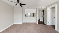 This single-floor residence offers a thoughtfully designed layout with a clean, modern aesthetic throughout. The open living area is generously sized, featuring warm neutral-toned carpet, a ceiling fan with integrated lighting, and large windows fitted with horizontal blinds that invite abundant natural light. A pass-through counter connects the living space seamlessly to the kitchen, which is outfitted with crisp white shaker-style cabinetry, white quartz countertops, a stainless steel refrigerator, electric range, over-the-range microwave, and dishwasher, all complemented by wood-look flooring for easy maintenance. A dedicated hallway leads to the bedroom, which continues the soft carpeting and neutral wall tones, with a window offering outdoor views. The hallway also provides access to a full bathroom, complete with a white vanity, large mirror, tub-shower combo, and a natural light window, as well as a closet for ample storage. A stacked washer and dryer unit is conveniently housed within the residence. White trim and doors, neutral taupe walls, and consistent finishes throughout create a cohesive and move-in ready environment.