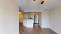 This single-floor residence offers a well-designed open-concept layout that connects the living area and kitchen seamlessly. Wood-style flooring runs throughout the main living spaces, providing a warm, cohesive aesthetic complemented by neutral-toned walls and clean white baseboards.

The kitchen is equipped with a full suite of stainless steel appliances, including a range, over-the-range microwave, refrigerator, and dishwasher. Light-toned cabinetry and speckled granite-style countertops provide ample workspace, while a peninsula with a breakfast bar separates the kitchen from the living area. A pendant light fixture and chandelier accent the dining and kitchen zones.

The living area is generously proportioned, featuring a ceiling fan and a sliding glass door that opens to a private balcony overlooking lush greenery, allowing abundant natural light to fill the space.

The bedroom includes wood-style flooring, a ceiling fan with light fixture, a large window offering scenic water and nature views, and a closet with bifold doors and built-in shelving. The bathroom features a single vanity with granite-style countertop, a large mirror with overhead lighting, and a tub-shower combination with tile flooring.