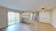 This single-floor residence offers a thoughtfully designed layout with a blend of modern finishes and functional living spaces. The open living and dining area is highlighted by light hardwood-style flooring, neutral-toned walls, and a ceiling fan overhead. A large sliding glass door fills the space with natural light and provides direct outdoor access. A pass-through kitchen connects seamlessly to the living area and features contemporary wood-grain cabinetry, white quartz-style countertops, recessed lighting, and a full suite of white appliances including a refrigerator, range, microwave, and dishwasher. Light hardwood-style flooring continues throughout the kitchen, adding a cohesive feel. The bedrooms are carpeted and generously sized, each offering ample wall space, natural light from windows, and access to closet storage. Two bathrooms serve the unit: one features a sleek tub-and-shower combination enclosed by a frameless sliding glass door, paired with a white vanity; the second is a compact yet well-appointed half-style bath with a modern vanity, mirror, and wall-mounted cabinet. Throughout the unit, clean white trim, neutral paint tones, and updated fixtures create a bright, move-in-ready atmosphere.