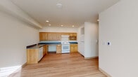 Located at 916 N 143rd St in Seattle, WA, this single-floor, three-bedroom, two-bathroom unit offers a functional and well-appointed layout. Light wood laminate flooring runs throughout, lending warmth and continuity to the space.

The kitchen is a standout feature, equipped with warm-toned wood cabinetry, bold navy blue countertops, a white electric range, dishwasher, and refrigerator. Recessed ceiling lights illuminate the generous counter and storage space, making it a practical area for cooking and meal preparation.

The three bedrooms are bright and neutrally finished, with large windows fitted with blinds that allow natural light to fill the rooms. The primary bedroom includes a ceiling fan and multiple windows, while another bedroom features built-in adjustable shelving for organized storage. A dedicated closet area with wall-mounted rails adds further practicality.

Both bathrooms are designed with accessibility in mind, featuring warm wood vanities with ample drawer storage, large mirrors, and grab bars. One bathroom includes a full soaking tub with a curved shower rod and multiple safety grab bars, while the other offers a toilet with side grab bar support.

Connecting the rooms are two hallways that ensure smooth flow throughout the unit. The overall design is clean, accessible, and move-in ready.