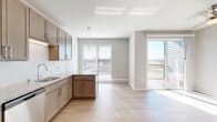 Located at Westgate Mall in Madison, WI, this single-floor residence offers a clean, contemporary design throughout. The open-concept kitchen and living area serves as the heart of the unit, featuring warm taupe cabinetry, granite countertops, a white subway tile backsplash, and a full suite of stainless steel appliances including a range, microwave, and dishwasher. Light hardwood-style flooring runs through the main living areas, enhancing the bright, airy atmosphere created by large windows and a glass sliding door that opens to a private balcony with outdoor views.

The hallway connects the main living space to the private areas of the unit and incorporates a convenient in-unit laundry closet housing a stacked washer and dryer. A stylish barn-style sliding door adds a modern architectural detail to the corridor. The bedroom features plush carpeting, a generously sized closet with built-in shelving, and ample wall space. The bathroom is finished with granite countertops on the vanity, a framed mirror, and a glass-enclosed shower stall, maintaining the consistent neutral and modern aesthetic found throughout the unit.