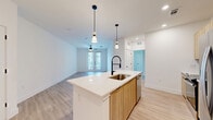 Located on McEwen Rd in Farmers Branch, TX, this thoughtfully designed one-bedroom, one-bathroom residence offers a modern and cohesive living experience across a well-utilized single floor. Light wood-tone flooring flows seamlessly throughout every room, contributing to a warm, airy aesthetic.

The open-concept kitchen and living area serves as the heart of the unit. The kitchen is outfitted with stainless steel appliances, including a gas range, microwave, and French door refrigerator, complemented by light wood cabinetry, a grey subway tile backsplash, and a white waterfall-edge island with a matte black faucet. Pendant lighting above the island adds a modern touch. The living area features a ceiling fan, recessed lighting, and a set of French doors that open to a private balcony, filling the space with natural light.

The bedroom is a comfortable, well-proportioned retreat with a ceiling fan, a window with outdoor views, and direct access to a dedicated walk-in closet equipped with built-in shelving and hanging rods.

The bathroom offers a clean, contemporary design with large-format tile surrounding a soaking tub and shower combination, matte black hardware accents, and wood-toned overhead cabinetry for added storage. The overall ambiance of the unit is bright, clean, and modern.
