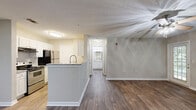 Located at 10100 Brown Bridge Road in Covington, GA, this well-appointed single-story home offers a thoughtfully designed layout that maximizes every square foot of its living space. The open-concept living and dining area greets residents with rich, dark hardwood-style flooring, neutral-toned walls, and a ceiling fan with integrated lighting — creating a comfortable and functional gathering space. Multiple windows allow natural light to filter in, offering pleasant views of the surrounding greenery. A glass-panel door provides direct access to the outdoors, enhancing the sense of openness.

The kitchen is a standout feature, boasting white cabinetry, granite-style countertops, a peninsula with a built-in sink, and stainless steel appliances including a range and refrigerator — ideal for everyday cooking and meal prep. Lighter hardwood-style flooring flows through the kitchen, complementing its bright, clean aesthetic.

The bedroom is a comfortable retreat, carpeted for warmth and equipped with a ceiling fan and a window overlooking lush outdoor scenery. A dedicated closet provides ample storage. The full bathroom features a tiled tub-shower combination, granite-topped vanity with white cabinetry, and hardwood-style flooring, maintaining the home's cohesive and modern design throughout.