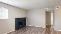 Located at 1401 N Midwest Blvd in Midwest City, Oklahoma, this one-bedroom, two-bathroom unit offers a practical and comfortable single-floor layout. The open living room serves as the heart of the home, highlighted by a striking dark-framed corner fireplace and durable wood-style plank flooring that extends throughout the main living areas. Natural light filters in through horizontal-blind-fitted windows, and a textured popcorn ceiling adds a classic residential touch.

The kitchen features gray cabinetry with brushed hardware, white countertops, a double-basin sink, and stainless steel appliances, all set on wood-style flooring for easy maintenance. A hallway connects the main living areas to the private spaces, and a dedicated laundry area with in-unit washer and dryer hookups adds everyday convenience.

The spacious primary bedroom is carpeted for comfort, fitted with a ceiling fan and light fixture, and receives natural light from a window with blinds. A closet provides organized storage. The two bathrooms are finished with wood-style flooring, white tile surrounds, tub-shower combinations, and vanities with light countertops. The overall aesthetic is clean, neutral, and move-in ready.
