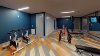 Located at 1989 Cheshire Bridge Rd NE in Atlanta, Georgia, this single-level fitness center offers a well-appointed workout environment designed to energize and motivate. The space is defined by bold navy blue accent walls that create a dynamic, focused atmosphere, complemented by striking geometric-patterned flooring in shades of orange, gray, and white that adds visual energy throughout the room.

The fitness center is equipped with a comprehensive free weight station, featuring a full rack of dumbbells in varying weights alongside adjustable workout benches, catering to a wide range of strength training exercises. A spin bike provides dedicated cardio options, while step platforms support group fitness and aerobic routines. Large wall-mounted mirrors along multiple walls visually expand the space and allow users to monitor their form during workouts.

Ceiling-mounted flat-screen televisions keep members entertained and informed during training sessions, while wall-mounted fans ensure proper air circulation throughout the space. A large whiteboard is available for workout tracking or instructional use, adding a functional touch. Atmospheric black-and-white athletic photography adorns the walls, reinforcing the space's fitness-forward identity. Linear LED lighting runs across the ceiling, providing bright, even illumination. The overall design balances practicality with modern style, creating an inviting and functional facility.