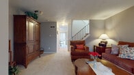 Located at 508–534 Long Blvd in Lansing, Michigan, this two-story residence offers a well-organized layout designed for comfortable everyday living. The main level features a carpeted living room with warm neutral-toned walls, providing a relaxed gathering space with easy access to a private patio area. A staircase with classic balusters connects the two floors, adding architectural character to the interior. Adjacent to the living room, a dedicated dining area accommodates a round wooden table with wrought-iron chairs beneath vertical blinds that allow natural light to filter in. The kitchen is equipped with rich wood cabinetry, stainless steel appliances including a range and over-the-range microwave, a double sink, and tile flooring, offering ample counter and storage space. A half bathroom on the main level provides convenience for guests, finished with a single-sink vanity and clean, simple fixtures. Upstairs, the generously sized primary bedroom features plush carpeting, multiple windows, and room for substantial furnishings. A full bathroom serves the upper level, complete with a single vanity, extended cabinetry, and a shower-tub combination. A large walk-in closet with built-in rod storage adds practical functionality to the upper floor.