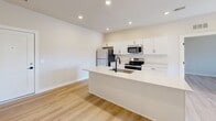 Located in Sterling Heights, MI, this thoughtfully designed 2-bedroom, 2-bathroom unit offers a clean, modern aesthetic across a single level. Light wood laminate flooring flows seamlessly throughout every room, creating a bright and cohesive feel. The open-concept kitchen is a standout feature, equipped with stainless steel appliances including a refrigerator, range, microwave, and dishwasher, complemented by crisp white shaker cabinetry, a white quartz peninsula with an undermount sink, and recessed lighting overhead. The spacious primary bedroom offers generous square footage and dedicated closet space, while the second bedroom features a window with blinds that allows natural light to filter in. Three closets total provide ample storage throughout the unit. Both bathrooms are finished with matte black hardware and fixtures — one includes a walk-in glass-door shower with built-in shelving, and the other features a tub-shower combo with sliding glass doors and a tiled surround. A dedicated laundry room houses a full-size stacked washer and dryer unit alongside a water heater. The overall design is clean and contemporary, with neutral tones and modern finishes throughout.
