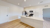 Located in Sterling Heights, MI, this thoughtfully designed 2-bedroom, 2-bathroom unit offers a clean, modern aesthetic across a single level. Light wood laminate flooring flows seamlessly throughout every room, creating a bright and cohesive feel. The open-concept kitchen is a standout feature, equipped with stainless steel appliances including a refrigerator, range, microwave, and dishwasher, complemented by crisp white shaker cabinetry, a white quartz peninsula with an undermount sink, and recessed lighting overhead. The spacious primary bedroom offers generous square footage and dedicated closet space, while the second bedroom features a window with blinds that allows natural light to filter in. Three closets total provide ample storage throughout the unit. Both bathrooms are finished with matte black hardware and fixtures — one includes a walk-in glass-door shower with built-in shelving, and the other features a tub-shower combo with sliding glass doors and a tiled surround. A dedicated laundry room houses a full-size stacked washer and dryer unit alongside a water heater. The overall design is clean and contemporary, with neutral tones and modern finishes throughout.