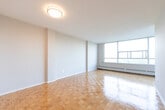 Located at 3165 Lawrence Ave E in Toronto's Scarborough neighbourhood, this one-bedroom, one-bathroom unit offers a well-organized layout across a single floor. Warm parquet flooring flows throughout the living room and bedroom, adding a classic character to the space.

The living room is bright and airy, anchored by a wall of large windows that flood the room with natural light and frame pleasant views of surrounding greenery. A glazed door leads to an enclosed balcony area, extending the sense of openness. A baseboard heating unit runs beneath the windows, ensuring year-round comfort.

The bedroom is a comfortable and well-proportioned retreat, featuring the same parquet flooring, a large double-door closet for ample storage, and a window offering pleasant outdoor views.

The kitchen is efficiently designed with grey cabinetry, granite-style countertops, a stainless sink, and white appliances including a full-size refrigerator and electric range. Tile flooring and abundant upper and lower cabinet storage make this a practical cooking space.

The bathroom is clean and straightforward, featuring a full tub-shower combination with white tile surround, a pedestal sink, and a mirrored medicine cabinet. A hallway connects all rooms, contributing to a logical and functional flow throughout the unit.