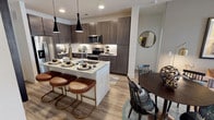 Located at 2019 Midway Rd in Lewisville, Texas, this single-story residence offers a thoughtfully designed layout with contemporary finishes throughout. The open-concept kitchen is a central highlight, featuring dark espresso cabinetry that extends to the ceiling for ample storage, granite countertops, a classic white subway tile backsplash, and a full suite of stainless steel appliances including a range, microwave, and refrigerator. A kitchen island with seating provides additional prep space and casual dining, illuminated by sleek pendant lighting overhead. Wood-look flooring flows seamlessly through the main living areas, complementing the neutral color palette.

The living area is welcoming and well-lit, with access to an outdoor space through glass doors that invite natural light. Multiple bedrooms feature plush carpeting, ceiling fans, and generously sized windows that frame outdoor views. Each bedroom benefits from direct access to a well-organized walk-in closet. The bathrooms mirror the kitchen's refined aesthetic, showcasing granite vanities with dark cabinetry, large mirrors, and tile-surround showers. One bathroom features a glass-enclosed shower, while another offers a tub-shower combination, both connected to spacious walk-in closets.