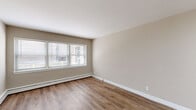 Located at 1550 N Prospect Ave in Milwaukee's vibrant East Side neighborhood, this one-bedroom, one-bathroom unit offers a thoughtfully arranged layout across a single floor. The living room is the largest area of the unit, featuring warm hardwood-style flooring, neutral taupe walls, and a wide multi-pane window that draws in natural light and provides views of the surrounding streetscape. Baseboard heating runs along the perimeter, ensuring consistent warmth throughout.

The kitchen is a standout feature, outfitted with crisp white shaker cabinetry, granite-look countertops, and a full suite of stainless steel appliances including a refrigerator, range, microwave, and dishwasher. Light wood-style flooring ties the kitchen seamlessly to the rest of the unit.

The bedroom is a comfortable, well-proportioned room with its own window, a ceiling fan, and a dedicated closet with a hanging rod. White walls and matching flooring maintain the unit's clean, consistent aesthetic.

The bathroom features bold deep-red ceramic wall tile, a white vanity with sink, a mirrored medicine cabinet, and a tub with shower. A central hallway connects all rooms efficiently, completing this practical and well-maintained unit.
