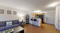 Located at 124 Ferry St in Troy, NY, this one-bedroom, one-bathroom unit offers a practical and well-organized single-floor layout. The open-concept living and kitchen area serves as the heart of the space, where warm hardwood-style flooring flows throughout. The kitchen is equipped with warm-toned wood cabinetry, granite-style countertops, black appliances including a side-by-side refrigerator, electric range, built-in microwave, and dishwasher. A breakfast bar with seating provides a casual dining option and naturally defines the transition into the living area. The living room features neutral white walls that lend a clean, bright ambiance, complemented by a window with curtains that invite natural light. The bedroom is a comfortable, carpeted retreat with a window allowing additional natural light, providing a quiet and restful atmosphere. The bathroom is finished with light tile flooring, a clean white vanity, and simple, functional fixtures. Throughout the unit, the design emphasizes efficiency and practicality, making it a straightforward and functional living space in the heart of Troy, NY.
