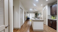 This thoughtfully designed one-bedroom, one-bathroom residence offers a functional and modern layout across a single floor. The open-concept kitchen and living area serves as the heart of the home, where rich dark-wood cabinetry, a mosaic tile backsplash, and stainless steel appliances — including a range, microwave, refrigerator, and dishwasher — create a polished and well-equipped cooking space. A granite-topped kitchen island with an integrated sink provides additional prep space and flows seamlessly into the living room. Wood-style flooring runs throughout the main living areas, adding warmth and continuity.

The living room is bright and welcoming, featuring a sliding glass door with vertical blinds that allows natural light to fill the space. The bedroom offers plush carpeting, a ceiling fan, and a window with exterior views, providing a comfortable and quiet retreat. A dedicated closet adds practical storage to the sleeping area.

The bathroom is finished with large-format tile flooring, a granite vanity with dark wood cabinetry, and a full tub-shower combination with tile surround. Recessed lighting throughout the residence ensures consistent, well-distributed illumination. The overall design balances modern finishes with functional living, making efficient use of the available space.