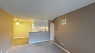 This single-story unit at 221 Smilax Rd in Vista offers a practical, well-organized layout connecting the living, dining, and kitchen areas in an open-concept design. The living room features neutral-toned carpet, a textured ceiling, and a wall-mounted AC unit, with a sliding glass door dressed in vertical blinds that allows natural light to fill the space. A ceiling fan is positioned in the adjacent dining area, which transitions to wood-look flooring.

The kitchen is separated from the living space by a peninsula counter with granite-style countertops, providing both workspace and a casual bar seating area. White shaker cabinetry, a stone tile backsplash, an undermount sink, and white appliances including a coil-top range, dishwasher, and refrigerator complete the kitchen.

The bedroom is a generously sized, carpeted room with a window fitted with vertical blinds, offering natural light and a textured ceiling overhead. The bathroom features wood-look flooring, a white shaker-style vanity with a bright vanity light strip and mirror, and a full-size tub and shower combination with a curtain rod, maintaining a clean, functional aesthetic throughout.