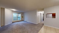 Located at 91 Michener Dr in Regina, Saskatchewan, this 2-bedroom, 2-bathroom unit offers a practical and comfortable single-floor layout. The living room is the heart of the space, featuring plush carpeting, a textured ceiling, and a sliding glass door that opens onto a private balcony with views of mature trees — allowing for generous natural light. A wall-mounted air conditioning unit and baseboard heating ensure year-round comfort. The galley-style kitchen is efficiently designed with warm wood cabinetry, ample upper and lower storage, laminate countertops, tile flooring, and full-sized white appliances including a refrigerator and electric range. The primary bedroom is a well-proportioned retreat with large windows, soft carpeting, and a baseboard heater. The second bedroom also features carpet and a built-in closet with louvred bifold doors. The main bathroom is notably spacious, offering a long granite-style countertop with dual sinks, individual mirrors, and tile flooring. A second bathroom includes a tiled tub-shower combination with a granite vanity. A hallway with built-in shelving provides additional storage. Neutral tones throughout give the unit a clean, move-in-ready feel.