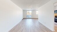This contemporary apartment, situated at 215 Champlain Blvd in Cambridge, Ontario, offers 770 square feet of thoughtfully designed living space. The open-concept layout seamlessly integrates the kitchen and living room, creating a spacious and airy atmosphere. Light wood laminate flooring runs throughout, complementing the crisp white walls and providing a modern aesthetic.

The apartment features two bedrooms, including a primary bedroom of 150 square feet, offering ample space for rest and relaxation. Large windows in the living area and bedrooms flood the space with natural light and provide pleasant views of the surroundings. The single bathroom boasts a clean, modern design with white subway tiles and a bathtub-shower combination.

The kitchen, while compact, is efficiently designed with sleek appliances and cabinetry. A hallway connects the various rooms, and a closet provides additional storage space. The unit's minimalist design, characterized by smooth white surfaces and simple lines, creates a blank canvas for personalization.

This single-floor apartment combines functionality with contemporary style, making it an ideal living space for those seeking a modern urban lifestyle in Cambridge.