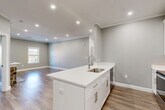This thoughtfully designed one-bedroom, one-bathroom residence in Chelmsford, MA offers a well-planned layout across a single floor. The open-concept kitchen and living area serves as the heart of the home, anchored by a large central island with white quartz countertops, an undermount sink, and brushed nickel fixtures. White shaker-style cabinetry pairs with a full suite of stainless steel appliances, including a refrigerator, range, and microwave. The living room is distinguished by a striking stone-surround fireplace, crown molding, recessed lighting, and natural light from a double-hung window. Hardwood-style flooring flows consistently throughout the entire space, tying each room together cohesively. A dedicated office provides a quiet, versatile space with its own window overlooking the outdoors. The bedroom is generously proportioned and features a walk-in closet with built-in shelving that connects directly to the full bathroom. The bathroom is finished with a white vanity, brushed nickel hardware, and a glass-enclosed walk-in shower. Additional storage is provided by multiple closets accessible from the hallway, rounding out this efficiently designed and attractively finished residence.