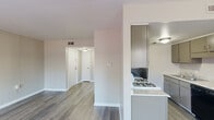 This single-story residence is designed with a practical, open layout that maximizes usable space throughout. Wood-look flooring in a warm gray tone runs consistently across the living areas and bedrooms, providing a cohesive and low-maintenance foundation. Neutral walls in soft beige and white tones create a bright, clean atmosphere throughout.

The galley-style kitchen is well-appointed, featuring granite-look countertops, taupe cabinetry offering ample storage, a gas range, black refrigerator, stainless steel sink, and a dishwasher. A partial wall separates the kitchen from the main living corridor, which flows openly toward the front entry and additional rooms.

The living and dining areas benefit from natural light, with windows fitted with blinds throughout. A glass-panel door leads directly to a private balcony, extending the living space outdoors. The bedrooms are generously sized, each with wood-look flooring, neutral walls, and built-in closets with shelving. One bedroom features a spacious wall of paneling, offering potential for creative use.

The bathroom is finished with a full tub-shower combo with white tile surround, a single vanity with mirror, and matching wood-look flooring. The overall ambiance is clean, functional, and move-in ready.