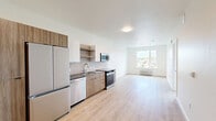 Unit 508 at Kinline is a thoughtfully designed one-bedroom residence that combines contemporary finishes with a functional single-floor layout. Light-toned luxury vinyl plank flooring runs throughout, unifying each area with a clean, cohesive aesthetic.

The open-concept kitchen and living area form the heart of the unit. The kitchen is outfitted with stainless steel appliances — including a French door refrigerator, dishwasher, range, and over-the-range microwave — complemented by two-tone cabinetry featuring warm wood-grain lower cabinets and white upper cabinets. A white subway tile backsplash and dark countertops add contrast, while open shelving provides practical display space.

The living area flows naturally from the kitchen, offering an open and airy feel with crisp white walls and ample room to arrange furnishings comfortably.

The spacious primary bedroom is generously proportioned and features large windows that frame views of the surrounding neighborhood, tree canopy, and distant hills, allowing natural light to fill the room. A wall-mounted mini-split unit ensures year-round comfort.

Additional features include in-unit laundry, as visible in the floor plan, recessed lighting, and a well-appointed bathroom accessible from the main corridor. The unit's clean, minimalist design makes it a versatile and move-in-ready space.
