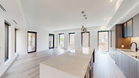 Located at Ridge Square NW in the desirable Northwest Washington, DC neighborhood, this thoughtfully designed two-bedroom, two-bathroom residence offers a generous and well-organized single-floor layout. Light hardwood flooring runs throughout, complementing the clean white walls and modern finishes that define the space.

The open-concept kitchen and living area serves as the heart of the home. The kitchen features sleek wood-grain cabinetry with under-cabinet lighting, a quartz countertop island with pendant lighting above, a matte black pull-down faucet, an integrated cooktop, and glass-front upper cabinets. The living area is bathed in natural light from floor-to-ceiling windows with dark frames, offering views of the surrounding brick architecture and greenery. A private balcony extends from this space, providing an outdoor retreat.

The primary bedroom is generously sized, with large windows that frame neighborhood views and ample closet space — the unit includes six closets in total. The second bedroom also benefits from large windows. Both bathrooms are finished with quartz vanities, wood-toned cabinetry, and matte black fixtures; the primary bath features a glass-enclosed walk-in shower. A light-filled hallway connects all areas of the home, reinforcing the residence's bright and airy ambiance throughout.