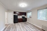 Located at 4 Parkway Rd, this well-appointed one-bedroom, one-bathroom unit is thoughtfully laid out across a single floor. The open-concept living, dining, and kitchen area forms the heart of the space, finished with light wood-style laminate flooring throughout and crown molding that adds a clean, classic touch. Multiple windows dressed with vertical blinds flood the area with natural light and offer views of surrounding greenery.

The kitchen is efficiently integrated into the main living area and features rich dark mahogany cabinetry, a gas range, refrigerator, under-cabinet range hood, and a sink with light stone-look countertops. A wall-mounted A/C unit and a classic cast-iron radiator provide year-round climate control.

The bedroom is a comfortable retreat with soft carpeting, a textured decorative ceiling, a ceiling fan with light fixture, a built-in closet with rod, and its own window with vertical blinds and A/C unit. The unit includes four closets in total, offering generous storage throughout.

The bathroom is clean and functional, featuring a full tub/shower combination with tile surround, a toilet, and a window for natural ventilation. The entrance provides a smooth transition into the main living space, completing this practical and well-maintained unit.