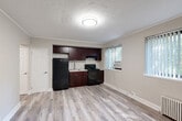 Located at 4 Parkway Rd, this well-appointed one-bedroom, one-bathroom unit is thoughtfully laid out across a single floor. The open-concept living, dining, and kitchen area forms the heart of the space, finished with light wood-style laminate flooring throughout and crown molding that adds a clean, classic touch. Multiple windows dressed with vertical blinds flood the area with natural light and offer views of surrounding greenery.

The kitchen is efficiently integrated into the main living area and features rich dark mahogany cabinetry, a gas range, refrigerator, under-cabinet range hood, and a sink with light stone-look countertops. A wall-mounted A/C unit and a classic cast-iron radiator provide year-round climate control.

The bedroom is a comfortable retreat with soft carpeting, a textured decorative ceiling, a ceiling fan with light fixture, a built-in closet with rod, and its own window with vertical blinds and A/C unit. The unit includes four closets in total, offering generous storage throughout.

The bathroom is clean and functional, featuring a full tub/shower combination with tile surround, a toilet, and a window for natural ventilation. The entrance provides a smooth transition into the main living space, completing this practical and well-maintained unit.