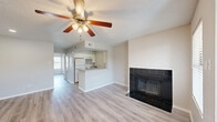 Located at 1595 S Old Orchard Ln in Lewisville, TX, this one-bedroom, one-bathroom residence offers a well-designed single-floor layout that maximizes every inch of its intimate footprint. Light wood-style flooring flows throughout the space, creating a cohesive and modern aesthetic. The open living area serves as the heart of the home, anchored by a striking black tile-surround fireplace and outfitted with a ceiling fan overhead. Natural light filters in through windows, lending the space a bright, airy feel. The kitchen is thoughtfully designed with white cabinetry, granite countertops, a stainless steel sink, and white appliances, and opens to the living area via a pass-through counter. The spacious bedroom features its own ceiling fan, a large window for natural light, and direct access to a dedicated closet and the full bathroom. The bathroom mirrors the kitchen's refined aesthetic with matching granite countertops, white cabinetry, and a large mirror. A separate laundry room with wire shelving and washer/dryer hookups adds everyday convenience. Textured ceilings and neutral-toned walls complete the clean, move-in-ready presentation throughout.