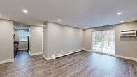 Located at 357 Newport Ave in Quincy, MA, this thoughtfully renovated one-bedroom, one-bathroom unit offers a clean, modern aesthetic throughout its efficiently designed single-floor layout. Wide-plank, hardwood-style flooring runs continuously through the living spaces, complemented by neutral gray walls, crisp white trim, and recessed lighting that creates a bright, welcoming atmosphere.

The open living room is a comfortable retreat, featuring a sliding glass door that invites natural light and provides access to the outdoors. Baseboard heating ensures year-round comfort, and a wall-mounted A/C unit is also present.

The kitchen is a standout feature, boasting dark granite countertops, two-tone shaker-style cabinetry in white and gray, a marble mosaic tile backsplash, stainless steel appliances including a gas range, dishwasher, and refrigerator, and a window for additional natural light.

The bedroom is a well-proportioned private space with a double-door closet, a natural light window with blinds, baseboard heating, and recessed lighting. Additional closet storage is also found near the unit's entry.

The bathroom is finished with floor-to-ceiling large-format tile surrounding a soaking tub and shower combination, a granite-top vanity, and a small window for ventilation. Every room reflects a cohesive, updated design throughout.