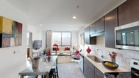 Located in the heart of Cincinnati's downtown at 1005 Walnut St, this single-floor residence showcases a contemporary urban design characterized by clean lines, an open layout, and abundant natural light. The living area is anchored by expansive floor-to-ceiling windows framed by exposed concrete columns, offering striking panoramic views of the Cincinnati skyline. Recessed lighting throughout complements the natural light, maintaining a bright and airy atmosphere.

The kitchen is thoughtfully designed with dark espresso cabinetry, white quartz countertops, and a classic subway tile backsplash. Stainless steel appliances—including a refrigerator, range, microwave, and dishwasher—provide modern functionality. A dedicated dining area adjacent to the kitchen offers additional space for entertaining.

An entry hallway connects the main living areas to the bedroom, which features its own floor-to-ceiling window framing elevated city views and a ceiling fan for added comfort. The neutral color palette, light flooring, and white walls create a cohesive, modern aesthetic throughout. The open-concept design seamlessly integrates the kitchen, dining, and living spaces, making the residence feel spacious and well-connected while maintaining a polished, urban character.