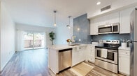 Located on Cahuenga Boulevard West in Los Angeles, this 2-bedroom, 3-bathroom residence offers a well-designed single-level layout. The open-concept living and dining area flows naturally into the kitchen, which features crisp white shaker cabinetry, a striking blue-gray textured accent wall, white quartz countertops, stainless steel appliances including a dishwasher, range, microwave, and refrigerator, and a peninsula with pendant lighting overhead. Light wood-style flooring runs throughout, lending warmth and continuity to the space. Sliding glass doors lead to a private balcony, bringing in natural light and outdoor views. The two bedrooms are bright and airy, with large windows and neutral walls offering a clean, versatile backdrop. Four closets provide ample storage throughout. The three bathrooms are finished with clean, classic tile work — one featuring a vessel sink vanity with large mirror and mosaic tile flooring, and another with a glass-enclosed walk-in shower with floor-to-ceiling white tile. An in-unit laundry area adds everyday convenience. The overall ambiance is modern, light-filled, and functional, making effective use of the available space.